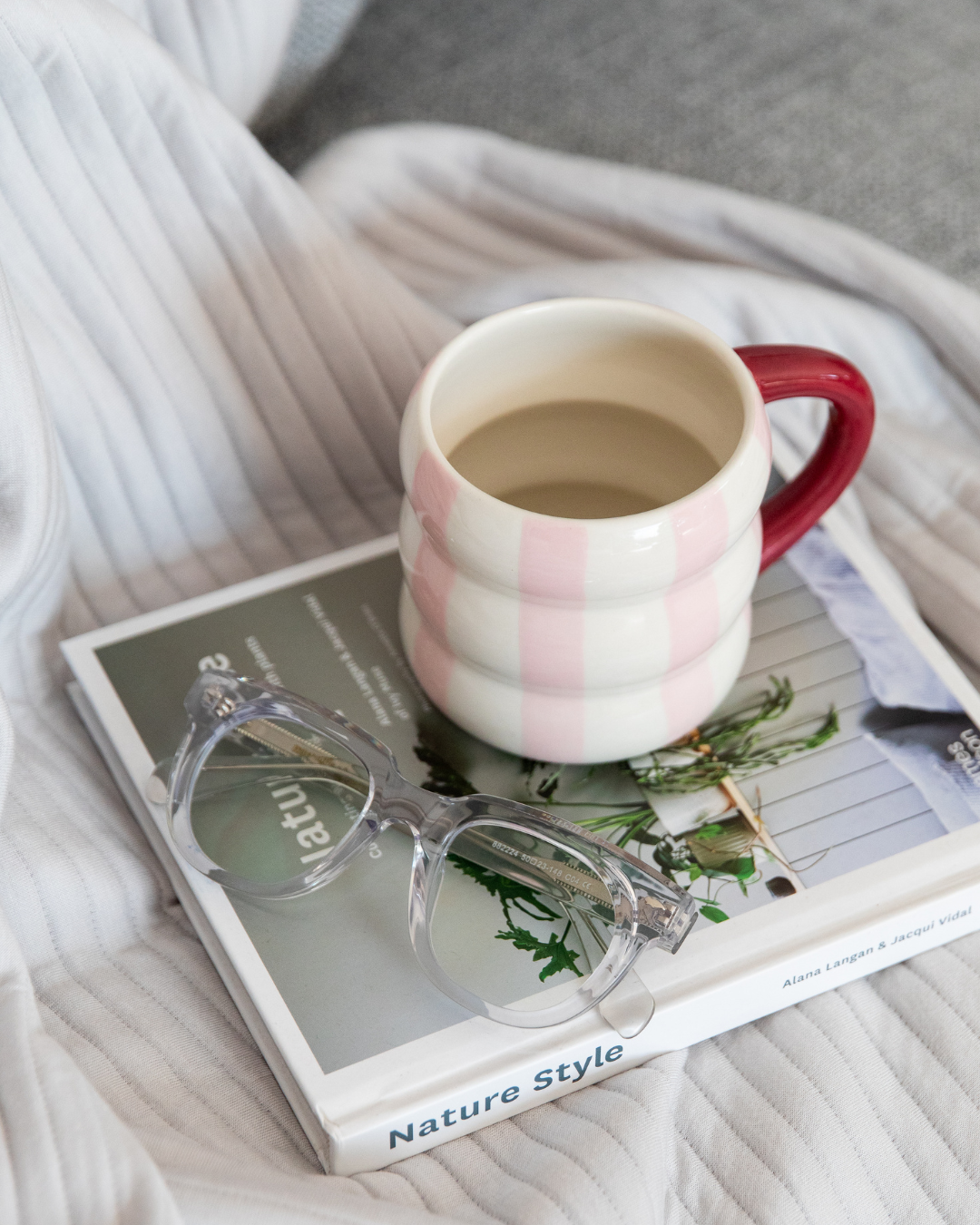 Mug with red handle on a book with stylish reading glasses - ministry of sight readers - clear reading glasses with blue-light blocking lenses
