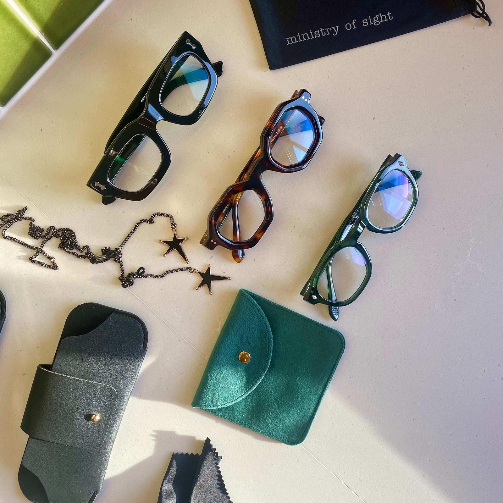 Flat Lay of three pairs of Ministry of Sight Reading Glasses and Rock Star glasses Chain and glasses cases