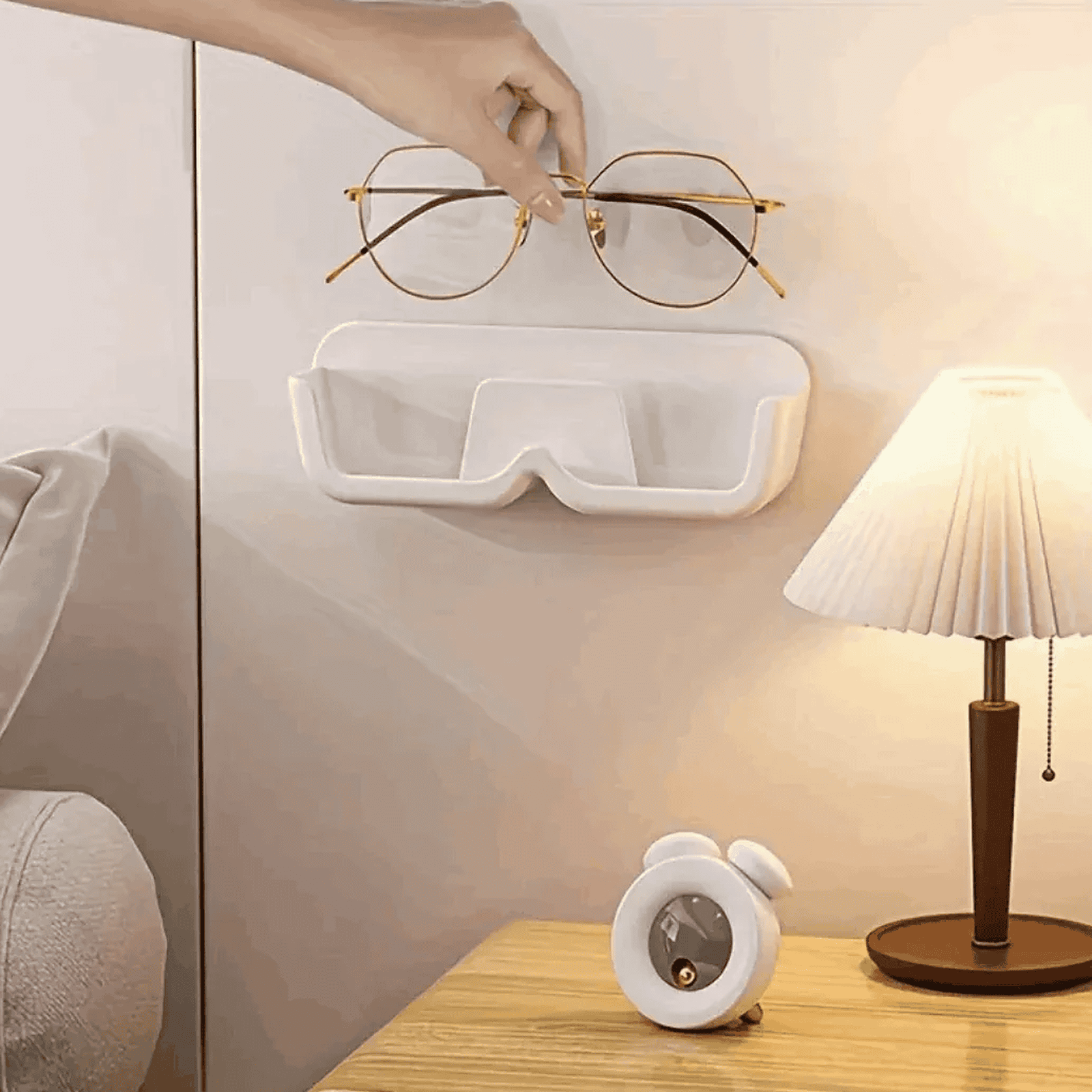 Glasses being placed on a white wall-mounted glasses holder in a bedroom setting - Ministry of Sight Lens Lounge wall storage for glasses