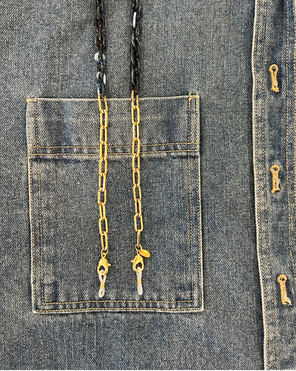 Close-up of a denim jacket with a front pocket, showing gold and navy blue glasses chain to keep your readers close. Look like jewellery. Ministry of sight