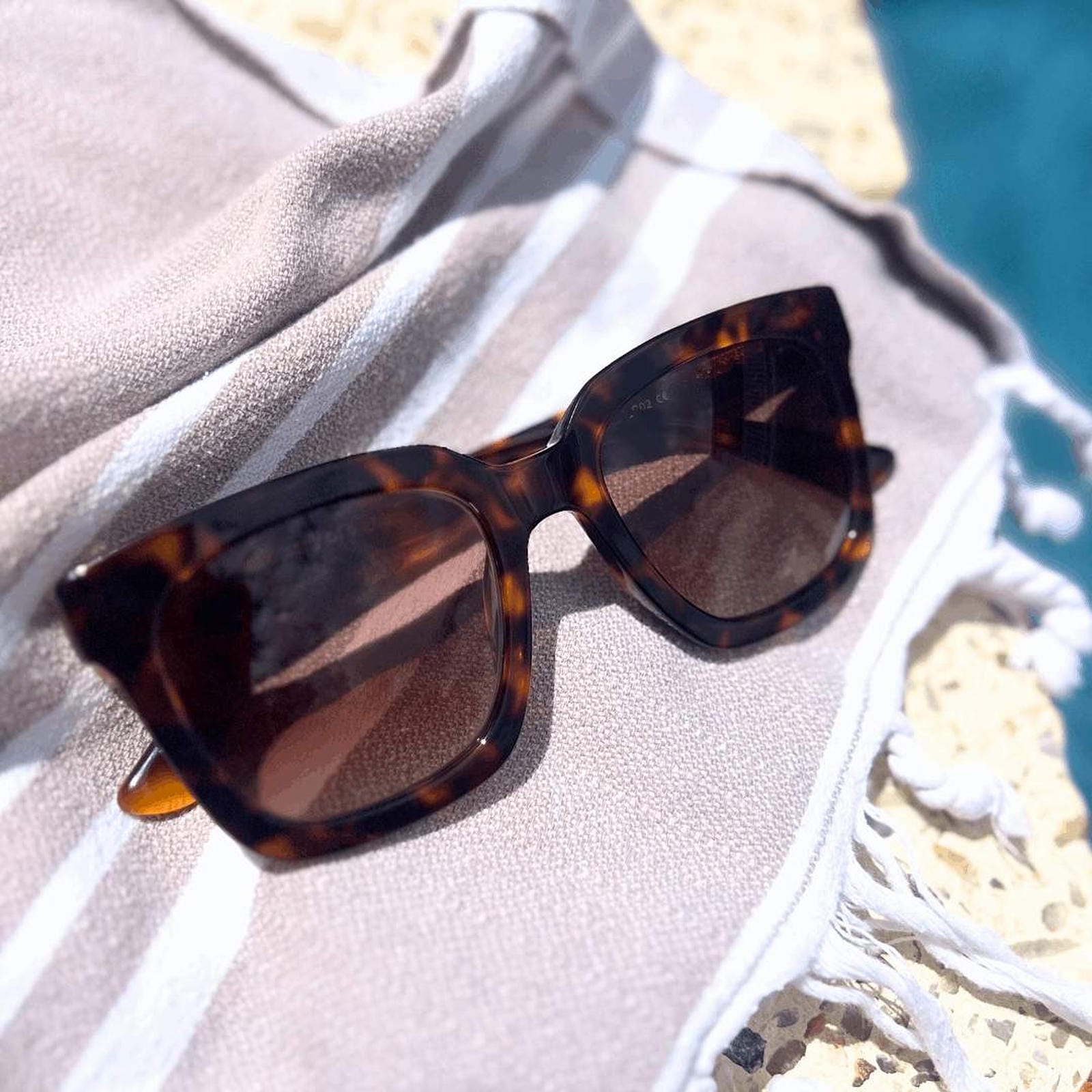 Tortoiseshell sun readers with progressive lenses and UV protection on a towel next to the pool in sun - Ministry of Sight Lumiere readers