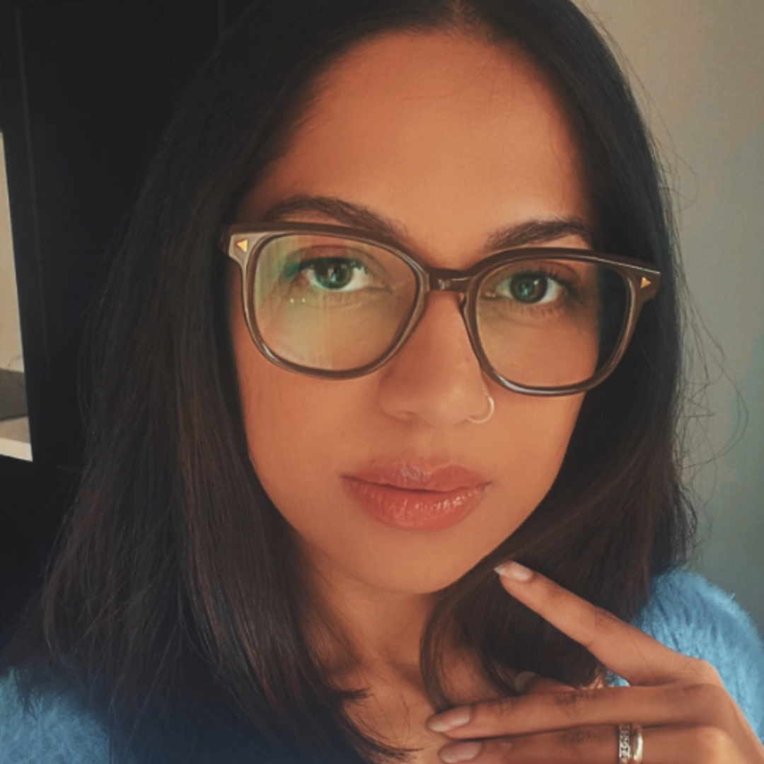 Australian woman wearing brown round reading glasses in blue jumper