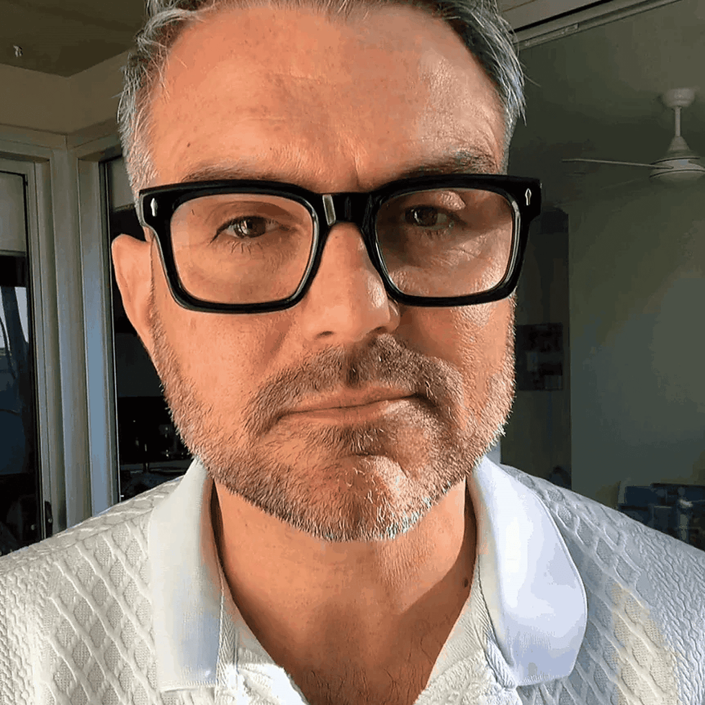 Australian stylish Man wearing black reading glasses and a white shirt 