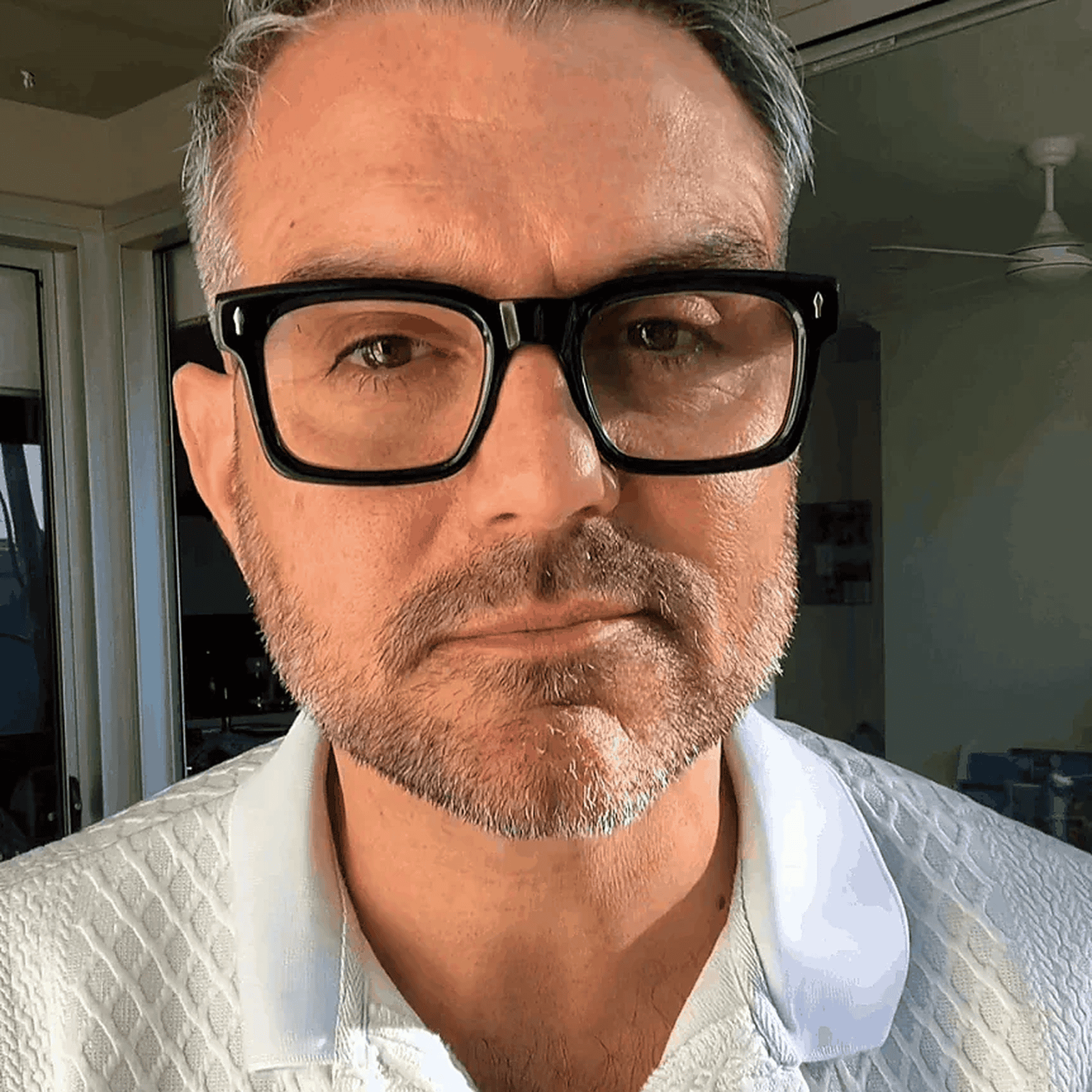 Australian stylish Man wearing black reading glasses and a white shirt 