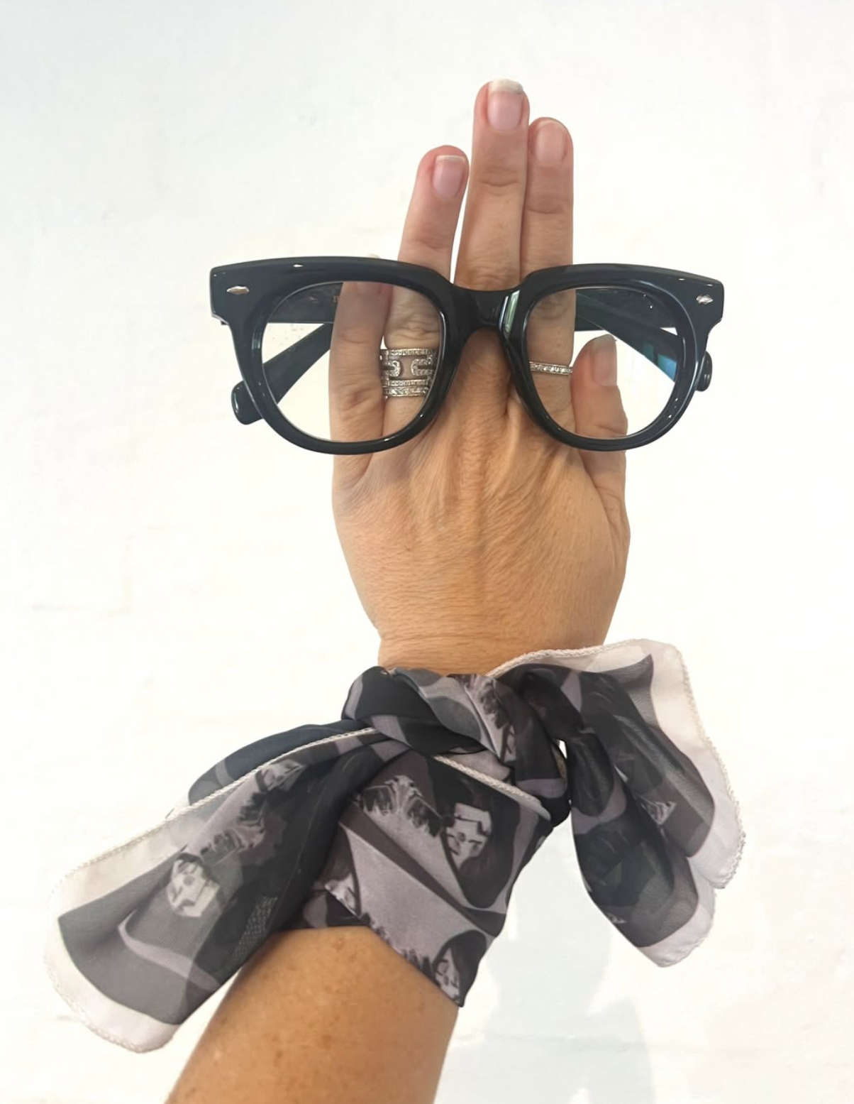 Hand holding up cool black round acetate reading glasses in Australia