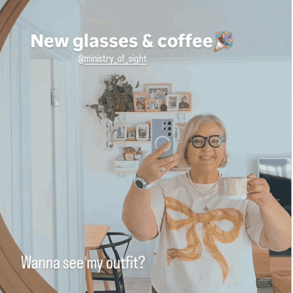 Australian woman over 50 in white bow top in stylish home wearing black frame flat top reading glasses - ministry of sight readers - new glasses and coffee - wanna see my outfit