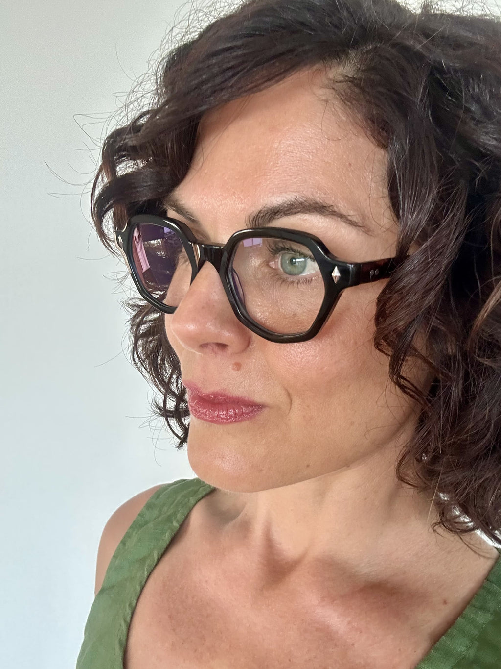Australian woman in a green top wearing The Heptagon reading glasses. Geometric brown and black reading glasses - ministry of sight readers