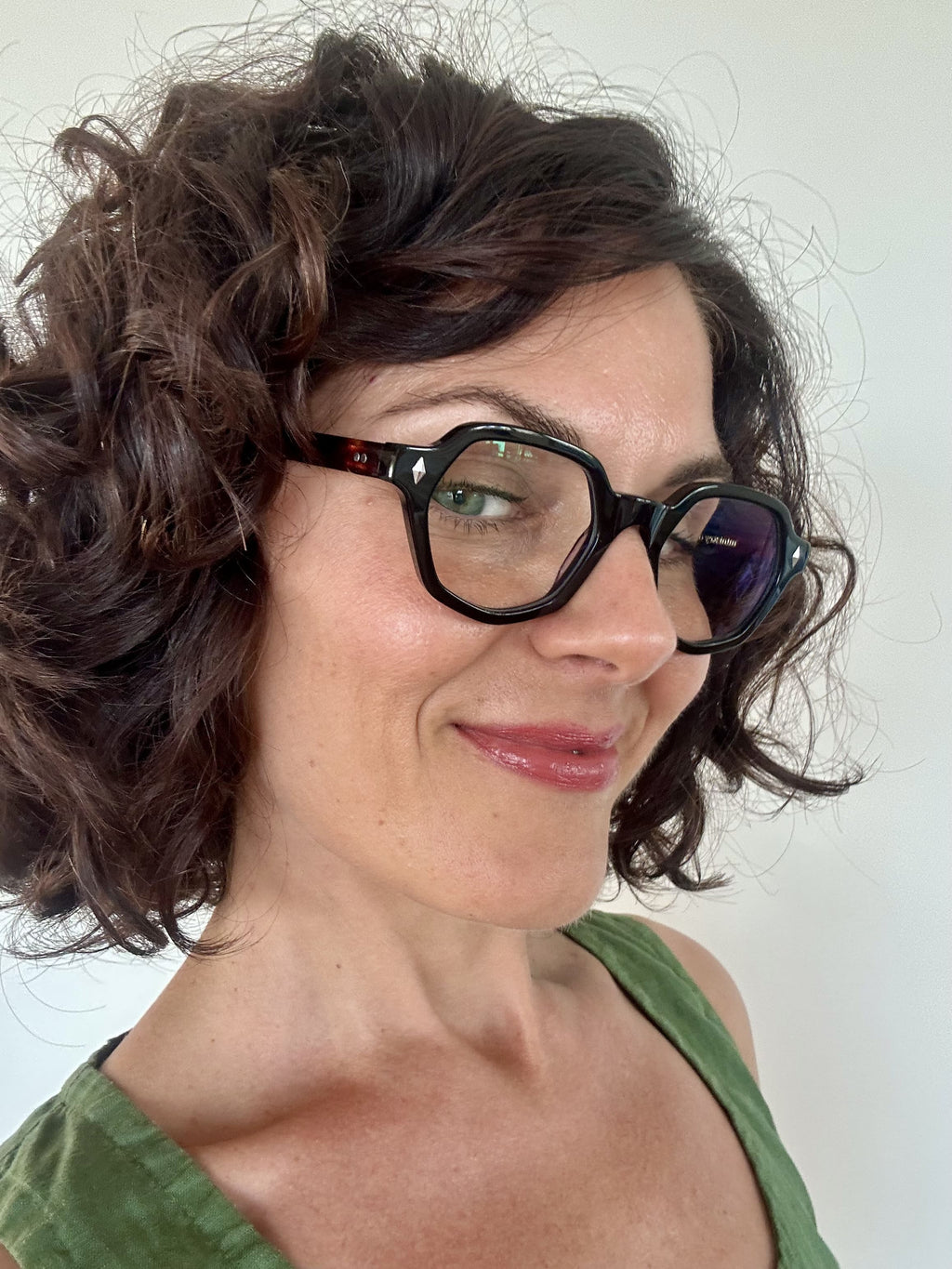 Australian woman in a green top wearing The Heptagon reading glasses. Geometric brown and black reading glasses - ministry of sight readers