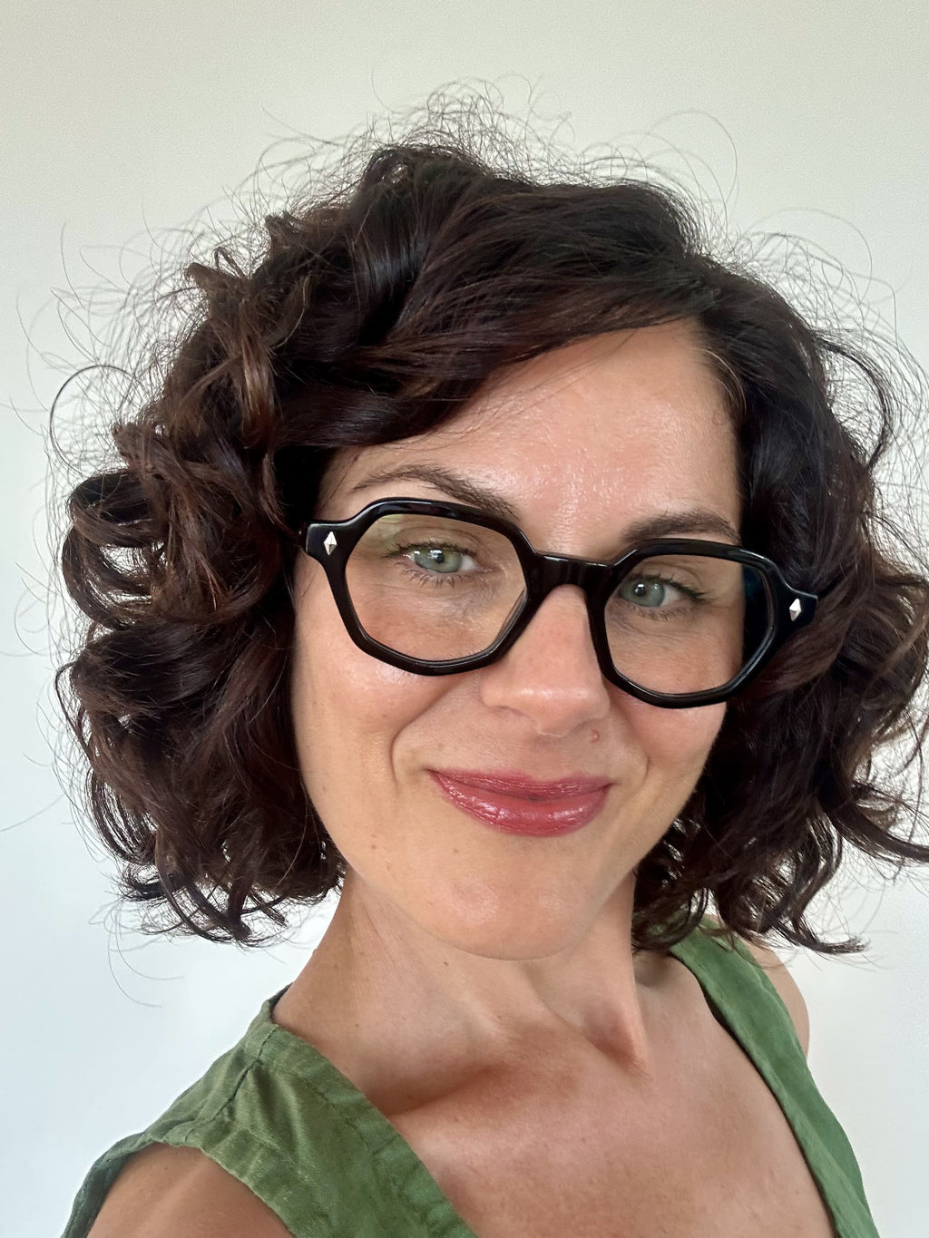 Australian woman in a green top wearing The Heptagon reading glasses. Geometric brown and black reading glasses - ministry of sight readers