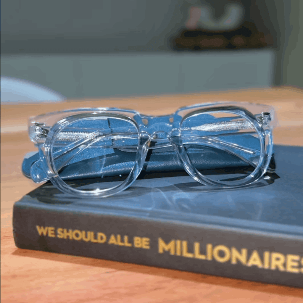 The Round clear reading glasses on a book titled we should all be millionaires - ministry of sight readers