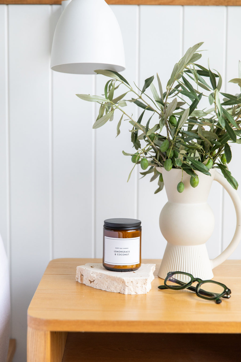 Candle, plant, and vintage style green reading glasses on a wooden surface on a bedside table - ministry of sight readers