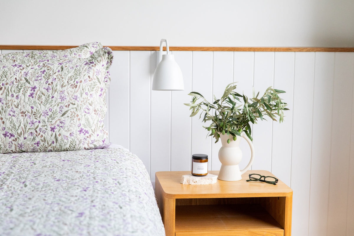 Bedroom with floral bedding, wooden nightstand, and decorative items including readers.