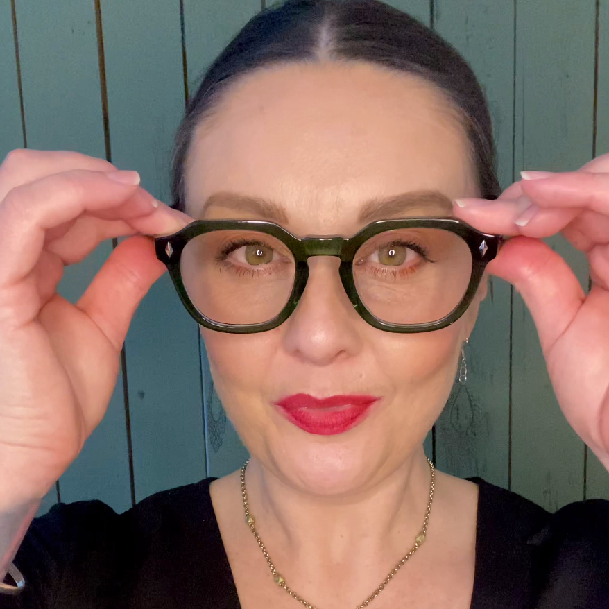 Person wearing green reading glasses with a plain background
